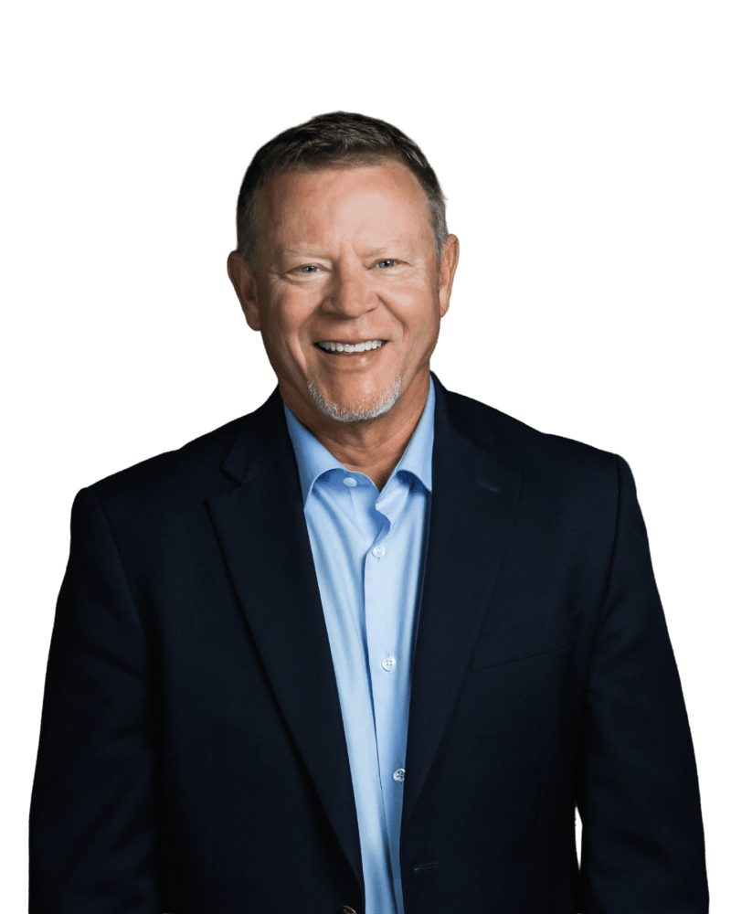 Smiling man with short hair wearing a navy blazer and light blue shirt against a white background
